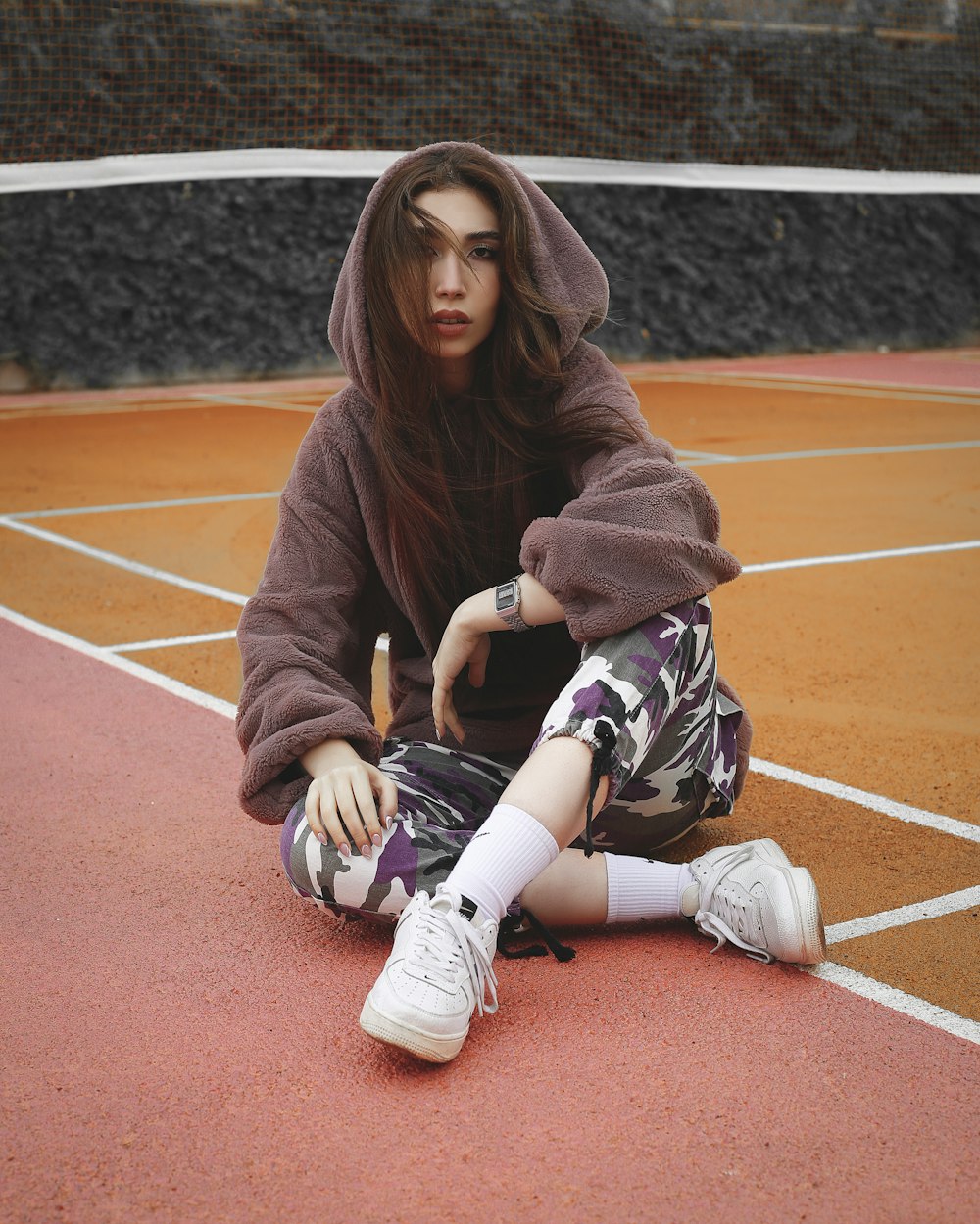 woman in brown sweater and white pants sitting on basketball court