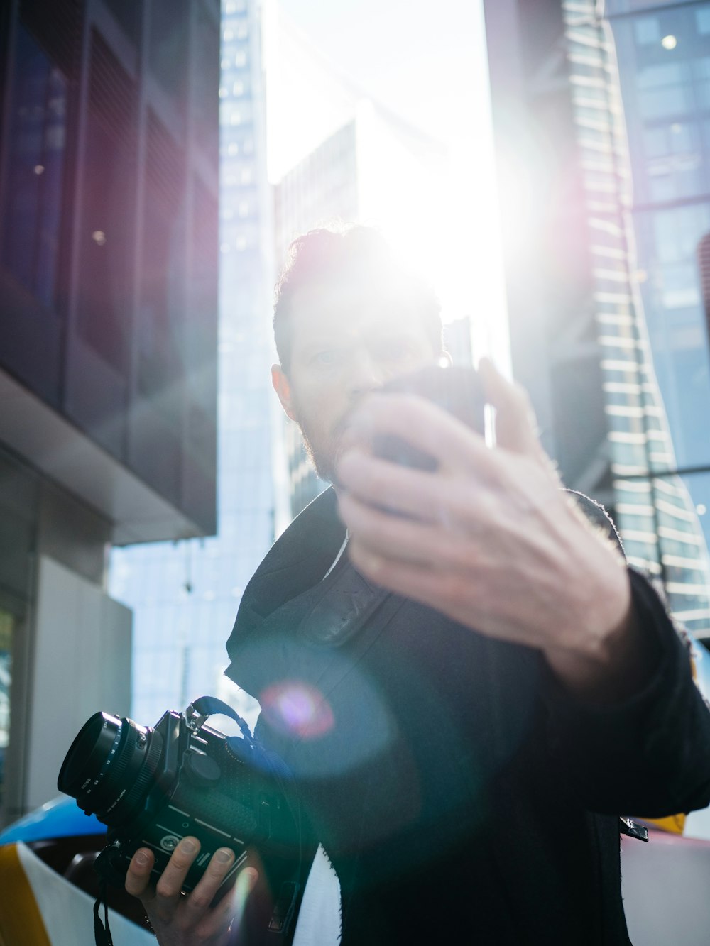 homem na jaqueta preta segurando a câmera dslr preta