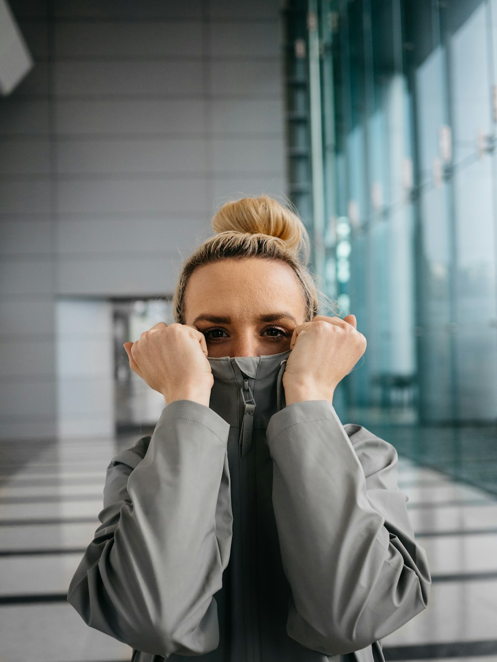 woman in gray coat covering her face with her hand