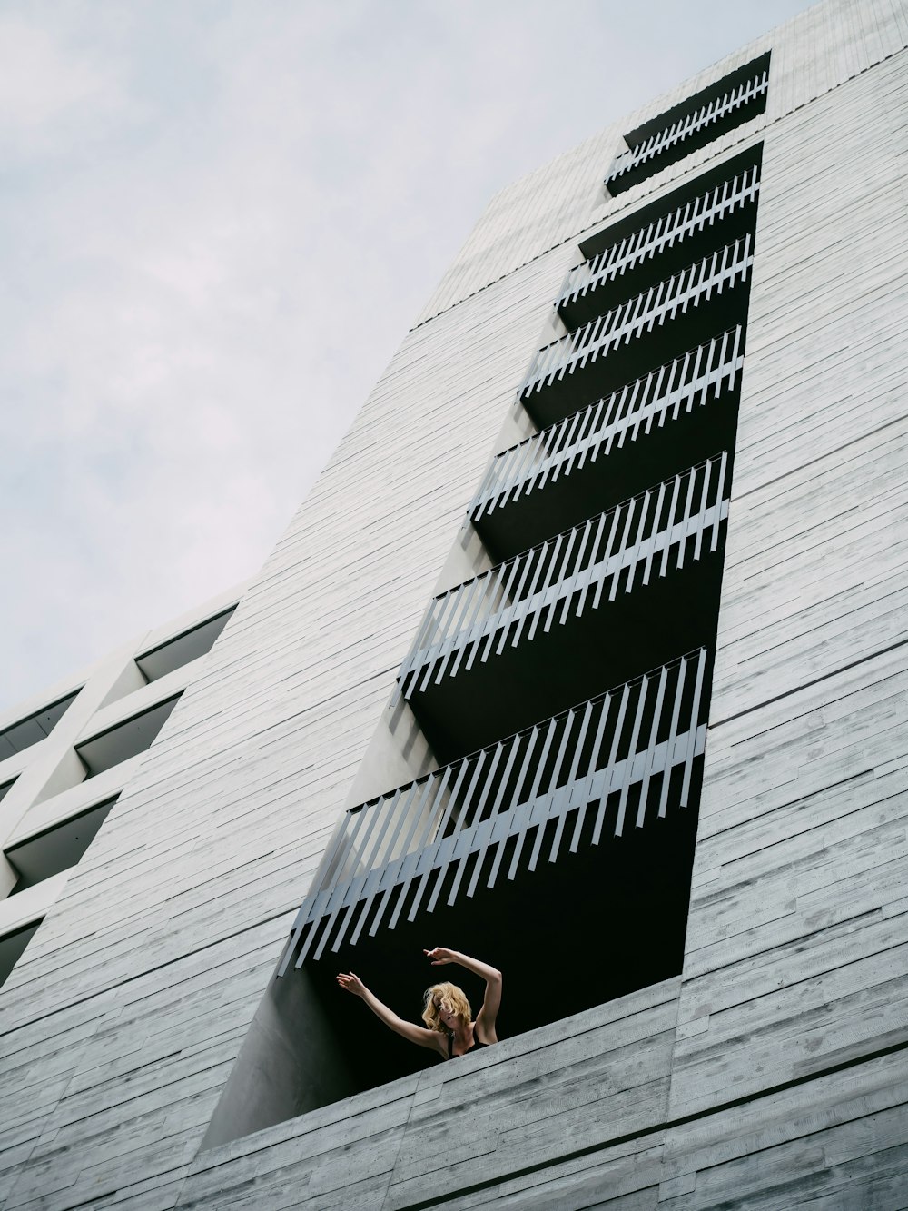 mulher na regata preta e shorts brancos sentados no edifício de concreto branco durante o dia