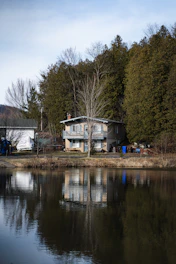 A friendly real estate agent handing keys to a happy family in front of their new home by a peaceful lake.