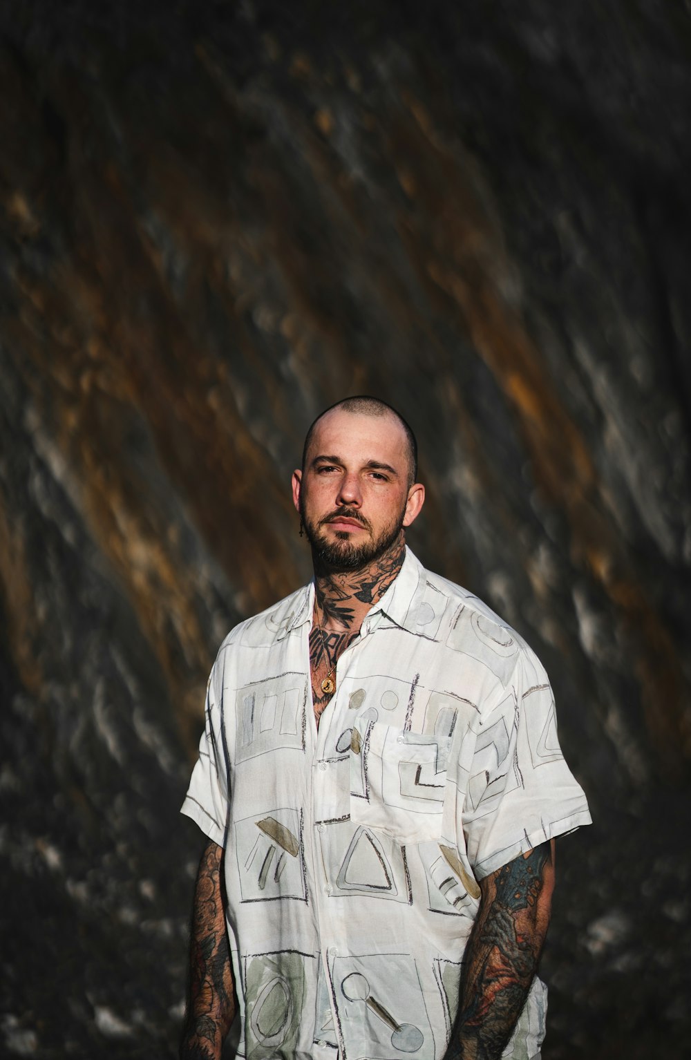 man in white and black plaid button up shirt standing near brown rock formation during daytime