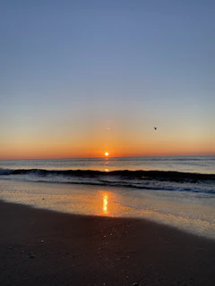 Golden sunrise casting warm light over a quiet Balinese beach with gentle waves