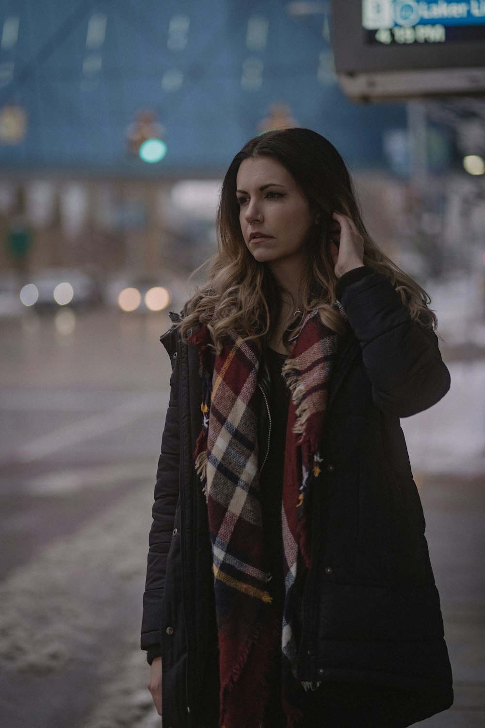 woman in black jacket standing on road during night time