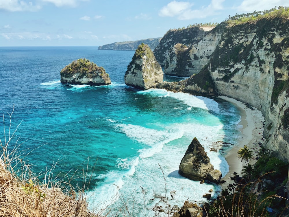 brown and green rock formation on blue sea under blue sky during daytime