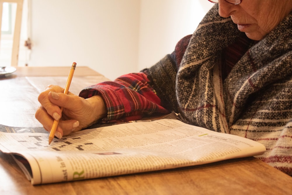 person in black and white sweater writing on white paper