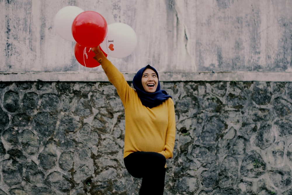woman in yellow long sleeve shirt holding red balloon