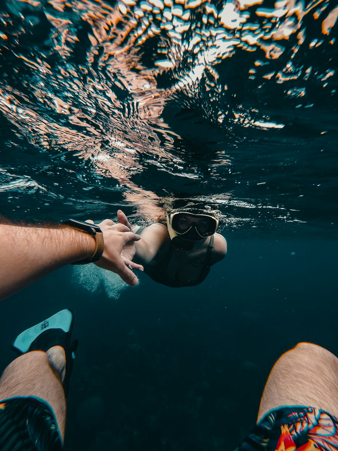 person in blue shorts holding black goggles in water