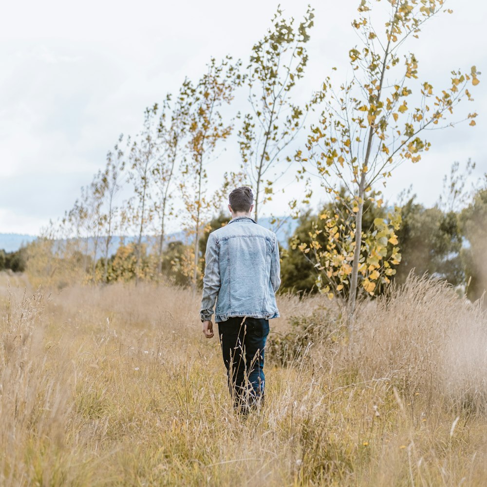 man in white hoodie standing on brown grass field during daytime