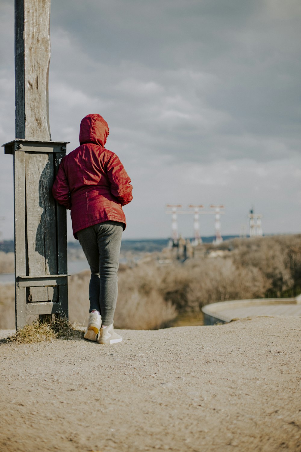 Woman in red hoodie and blue denim jeans standing beside gray wooden post  during daytime photo – Free Clothing Image on Unsplash