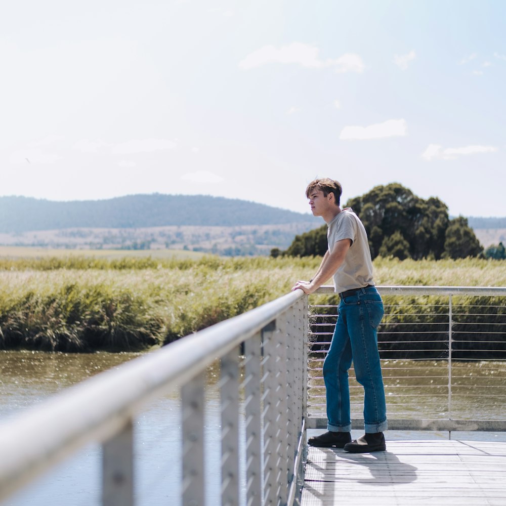 woman in white tank top and blue denim jeans standing on dock during daytime