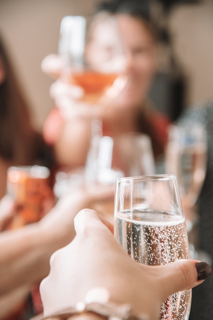 Close-up of hands clinking glasses of different beverages in a toast.