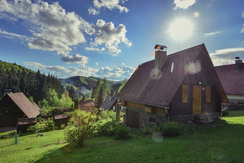 casa marrom e cinza perto de árvores verdes sob o céu azul durante o dia