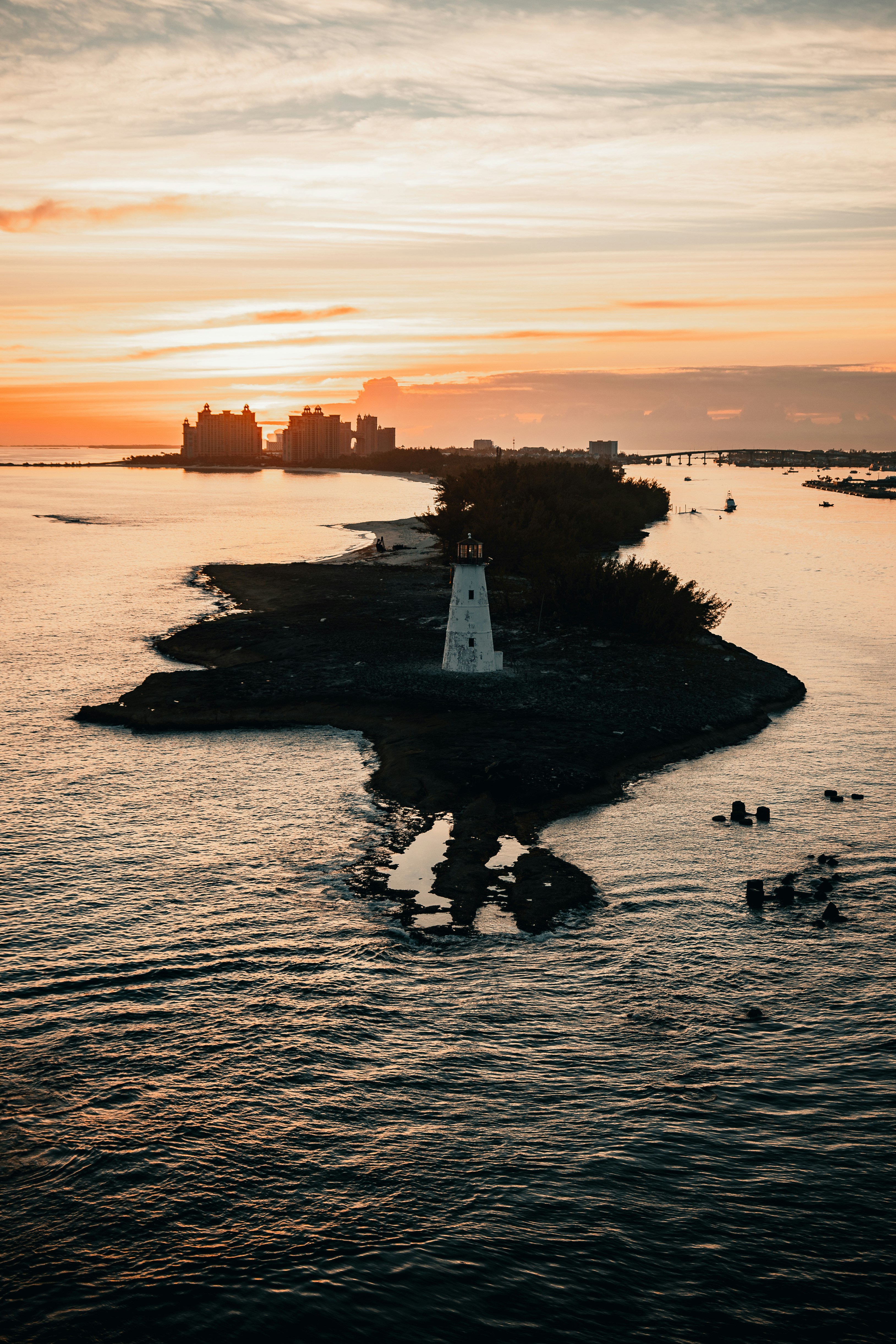 white and black lighthouse on body of water during sunset