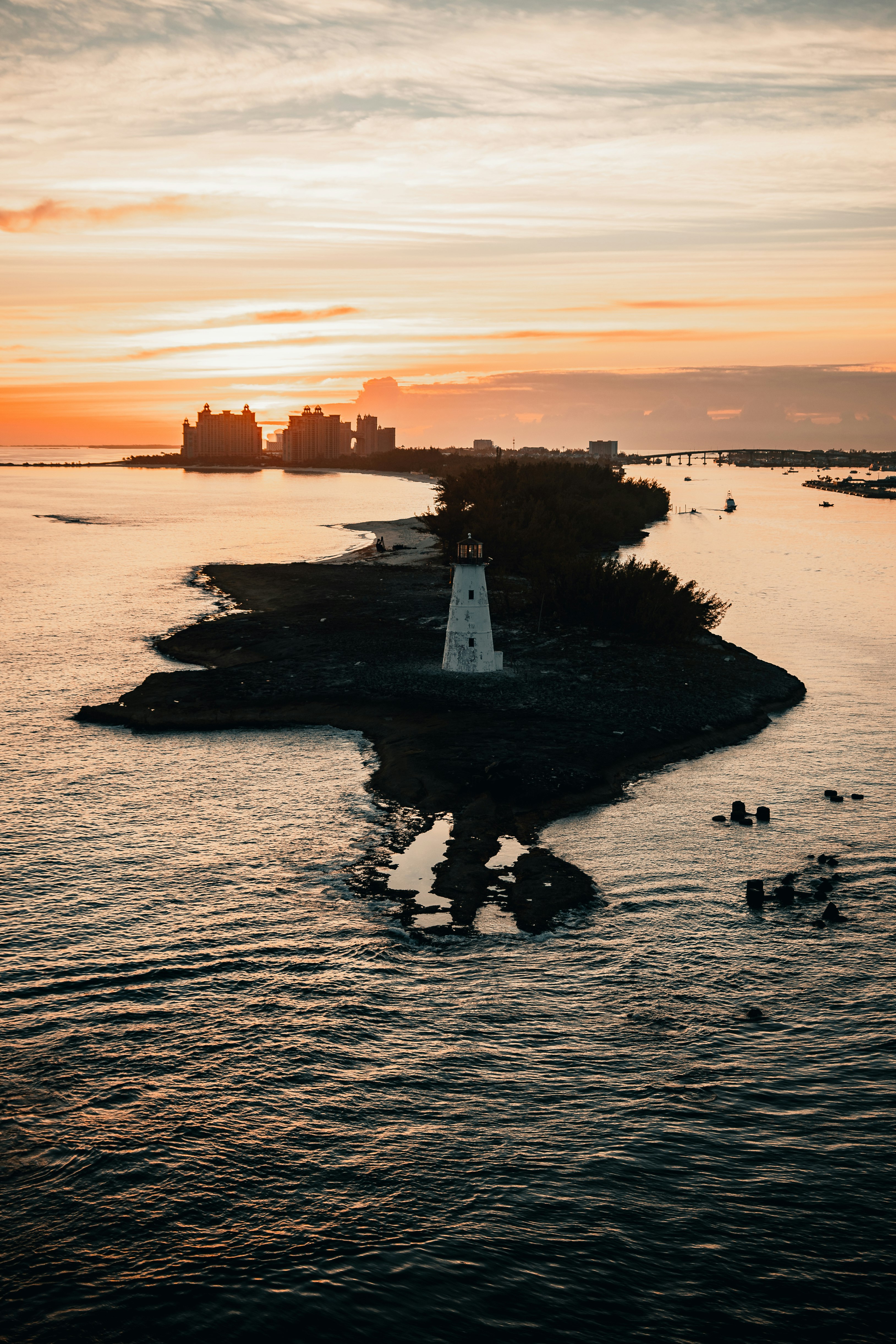 white and black lighthouse on body of water during sunset