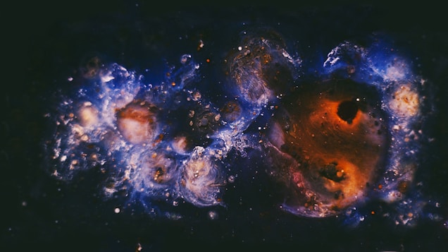 Swirls of vibrant colors, primarily blues and reds, merge to create an abstract cosmic scene resembling galaxies and nebulae. The mixture of bright and dark shades gives a sense of depth and vastness.