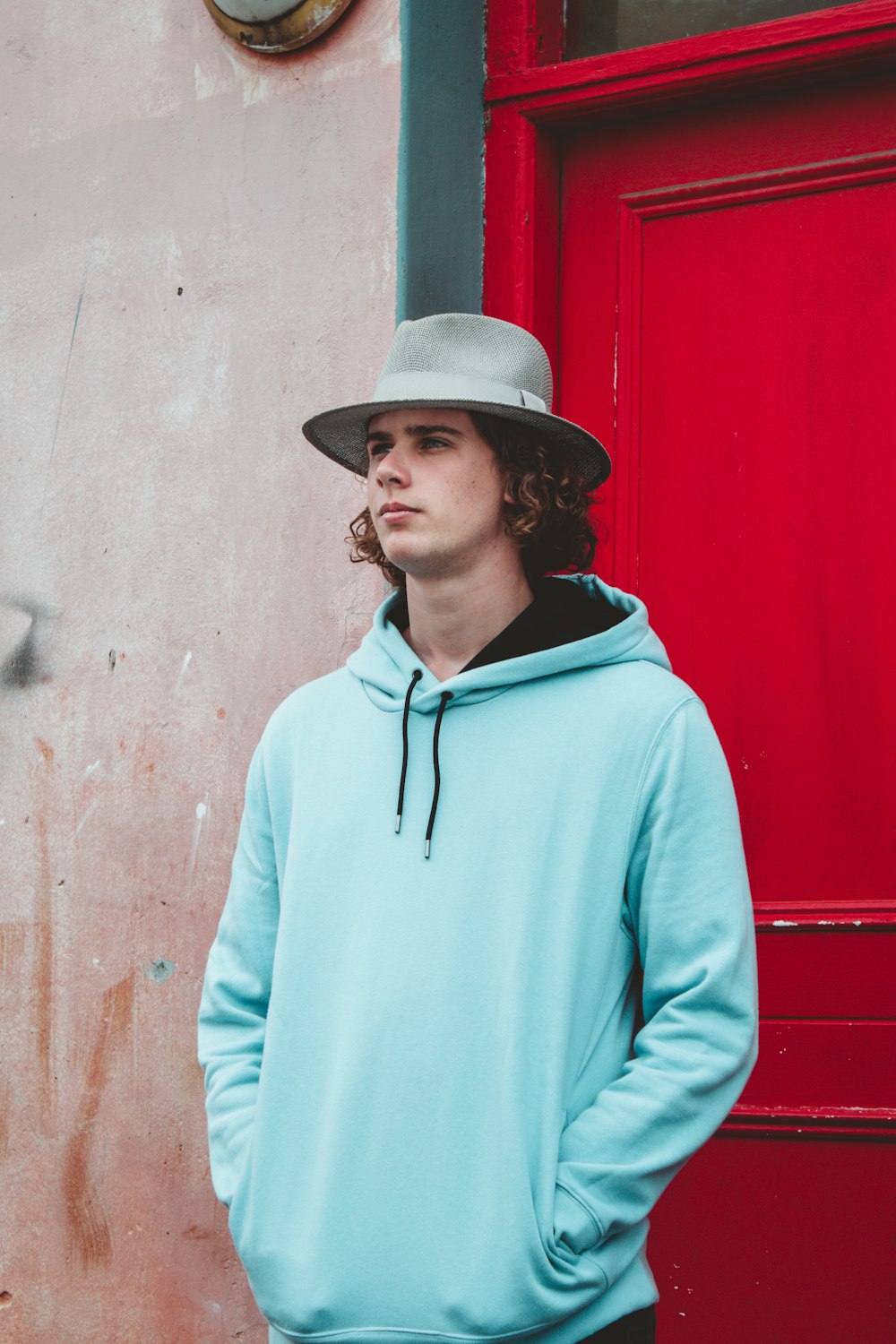 man in blue hoodie wearing brown fedora hat