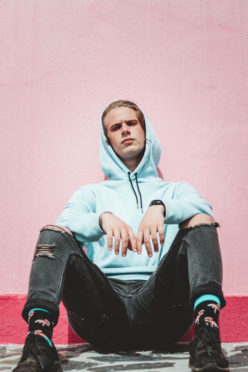 man in white hoodie and black pants sitting on red concrete bench