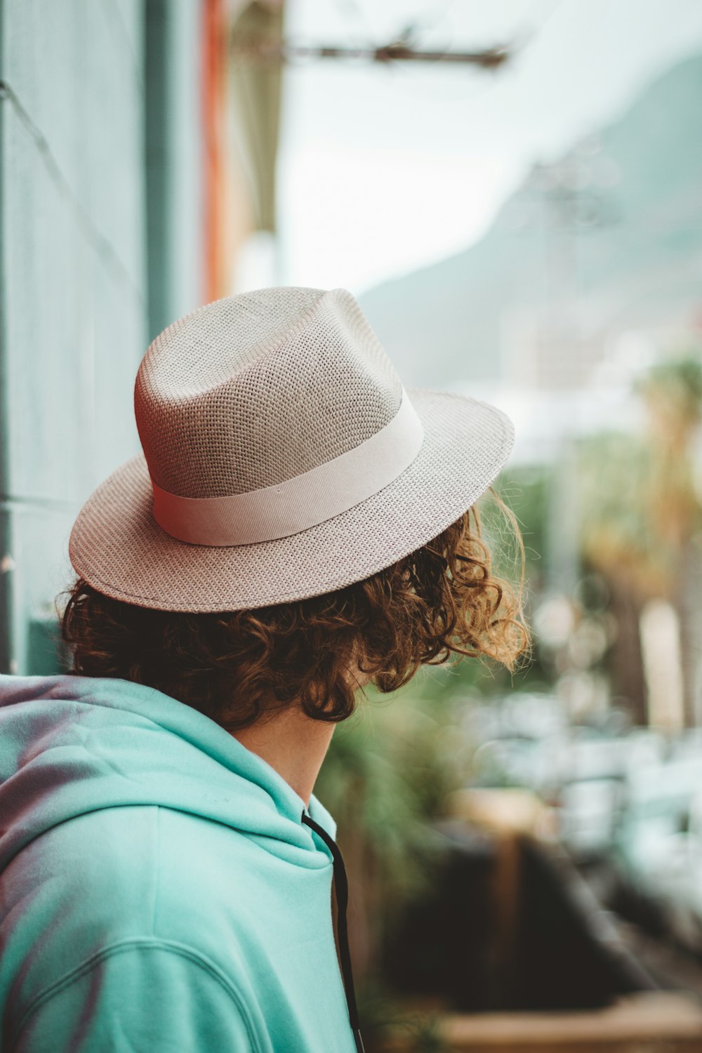 woman in green hoodie wearing brown fedora hat