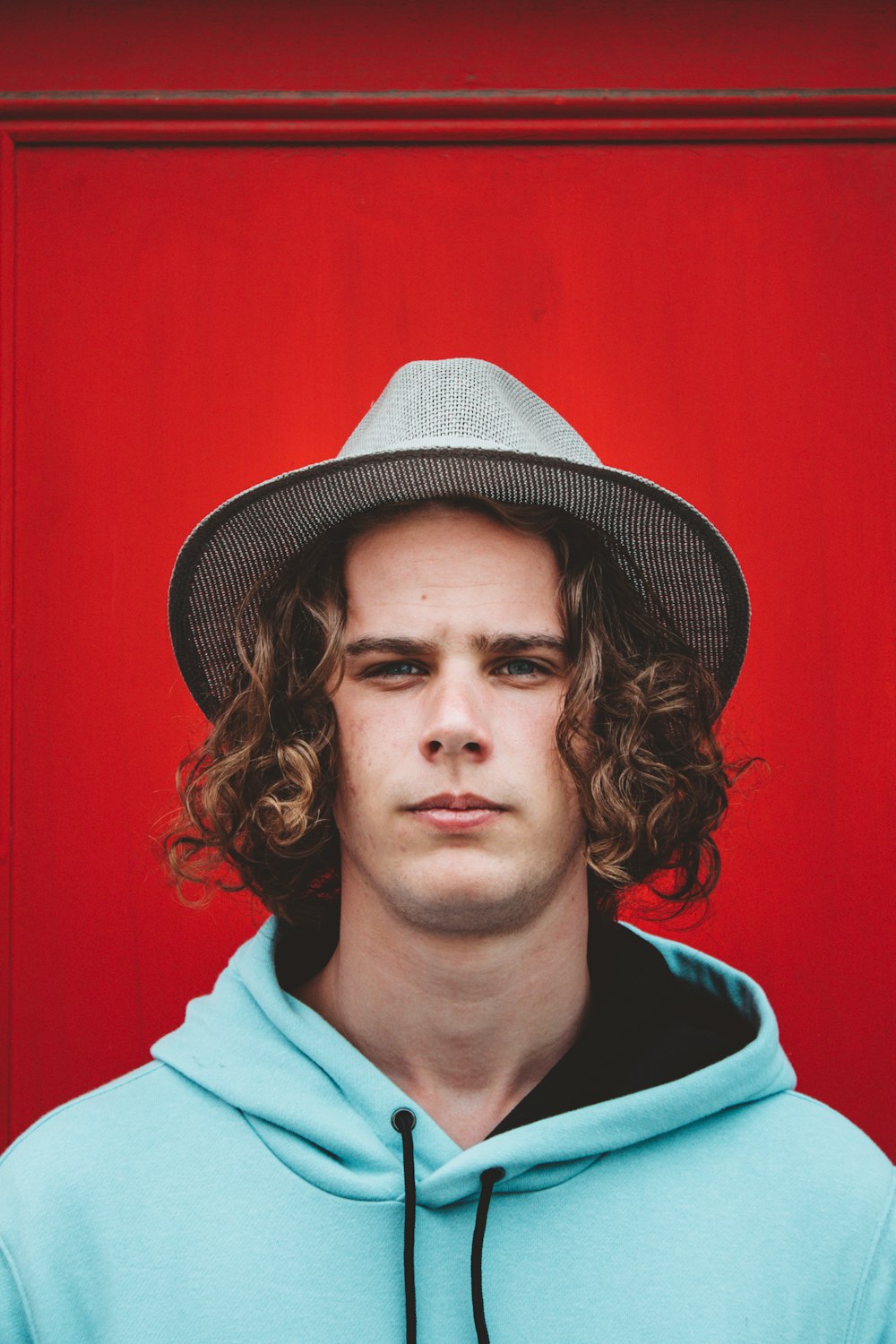 man in blue hoodie wearing black and white fedora hat