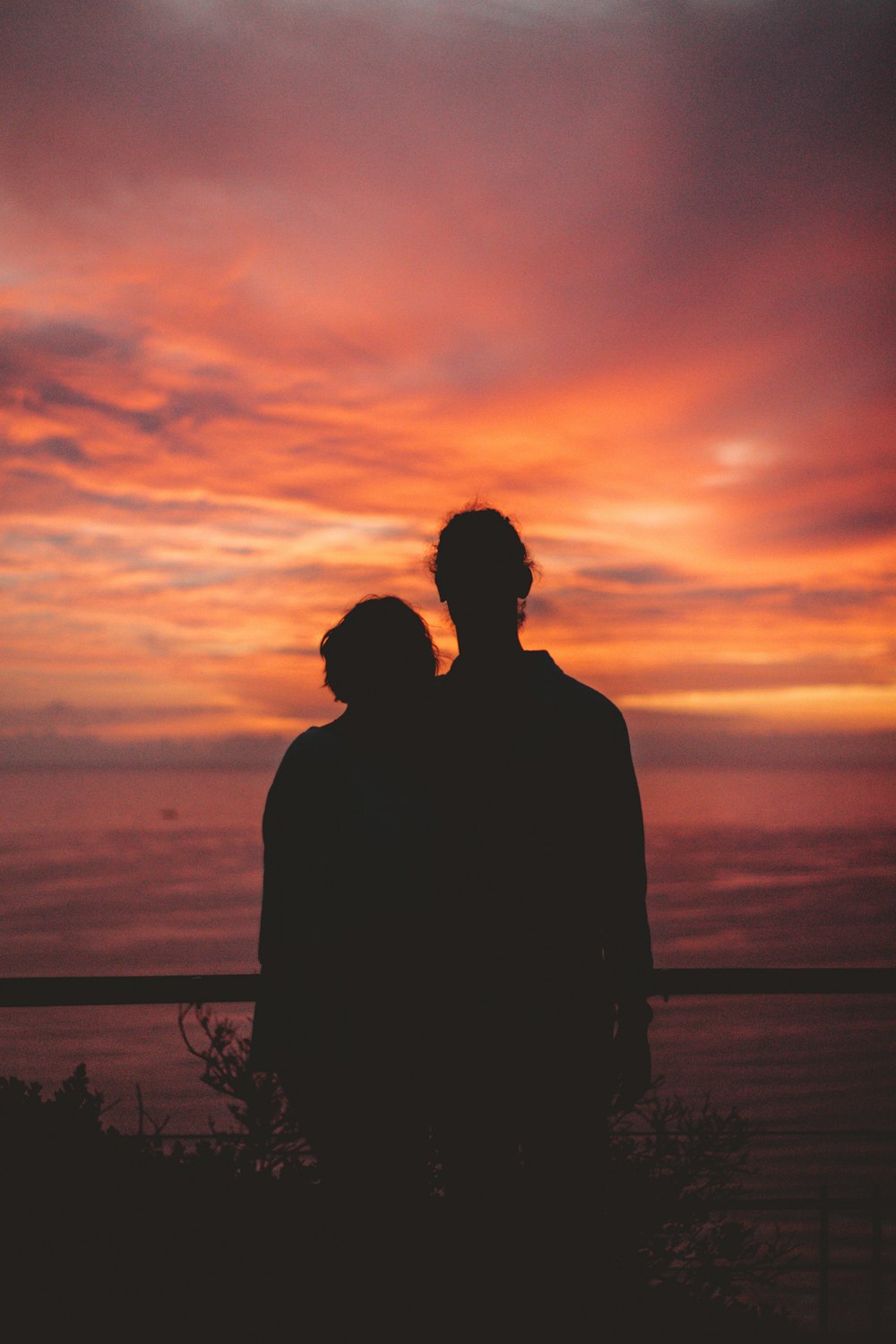 silhouette of man standing near body of water during sunset