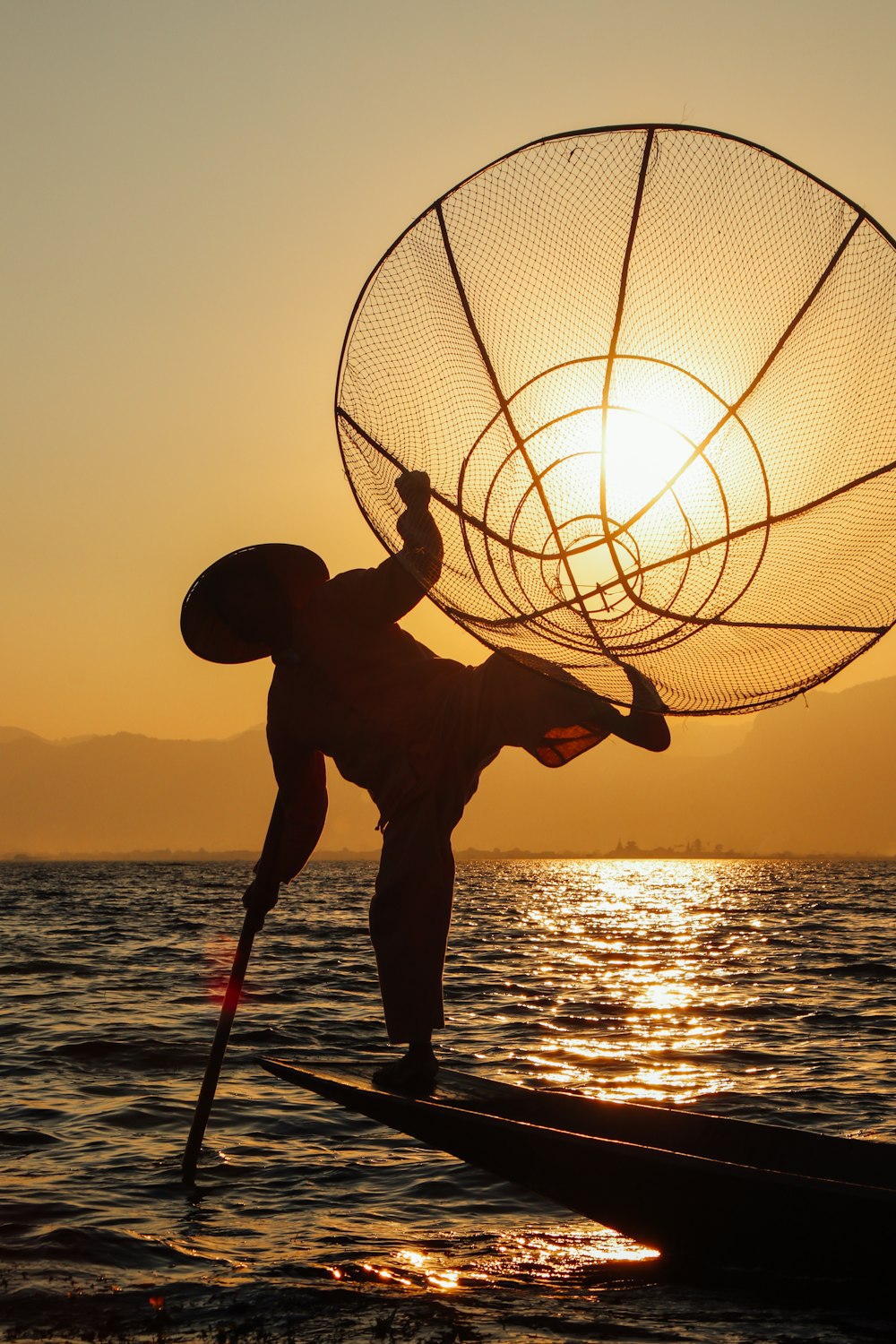 Silueta de hombre sosteniendo baloncesto durante la puesta del sol