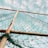 A net is stretched between rusty metal poles with a sky filled with clouds in the background. The net appears tangled at the bottom and is colored green.