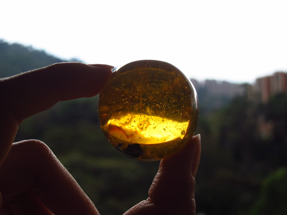 person holding gold round ornament