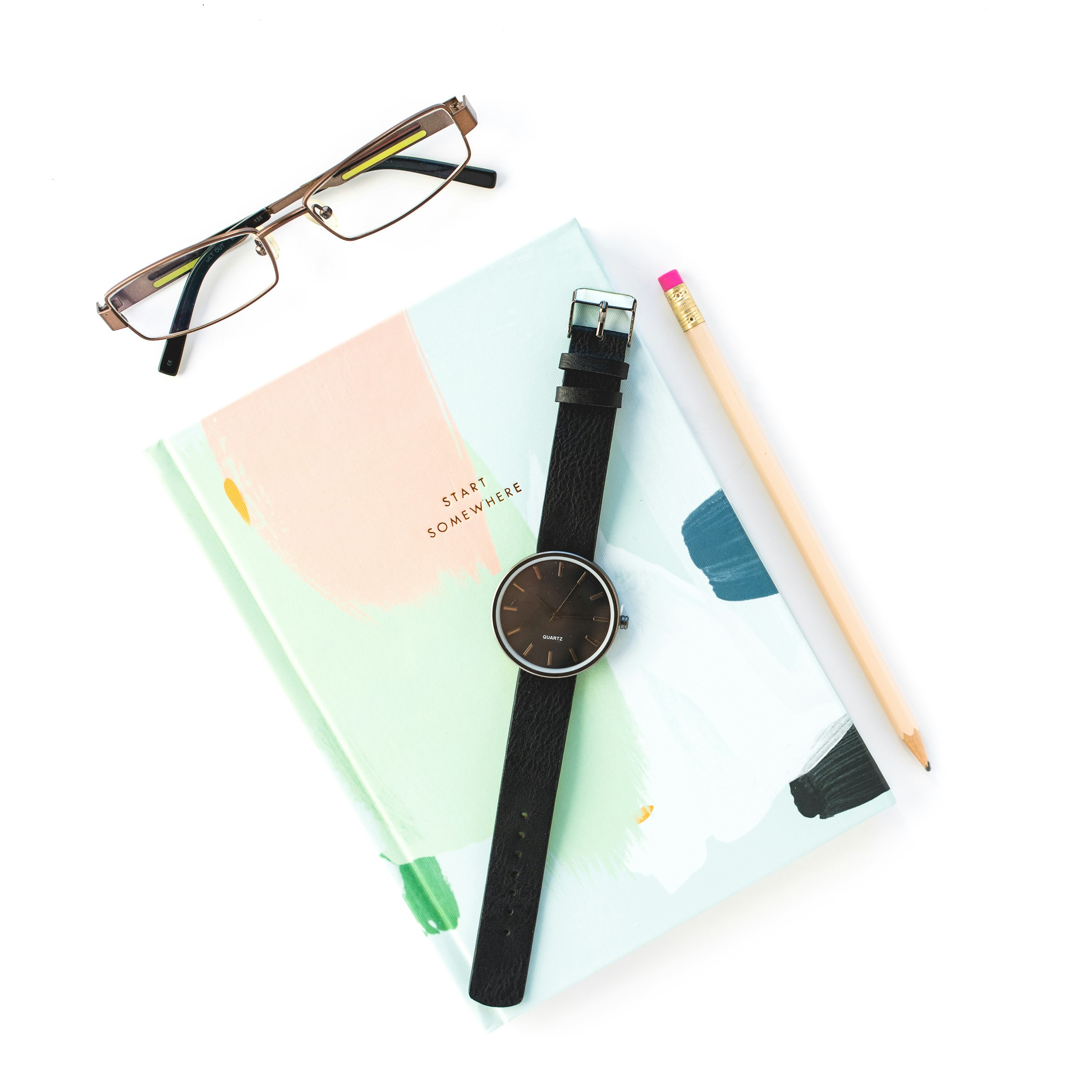 black framed eyeglasses beside blue and pink book