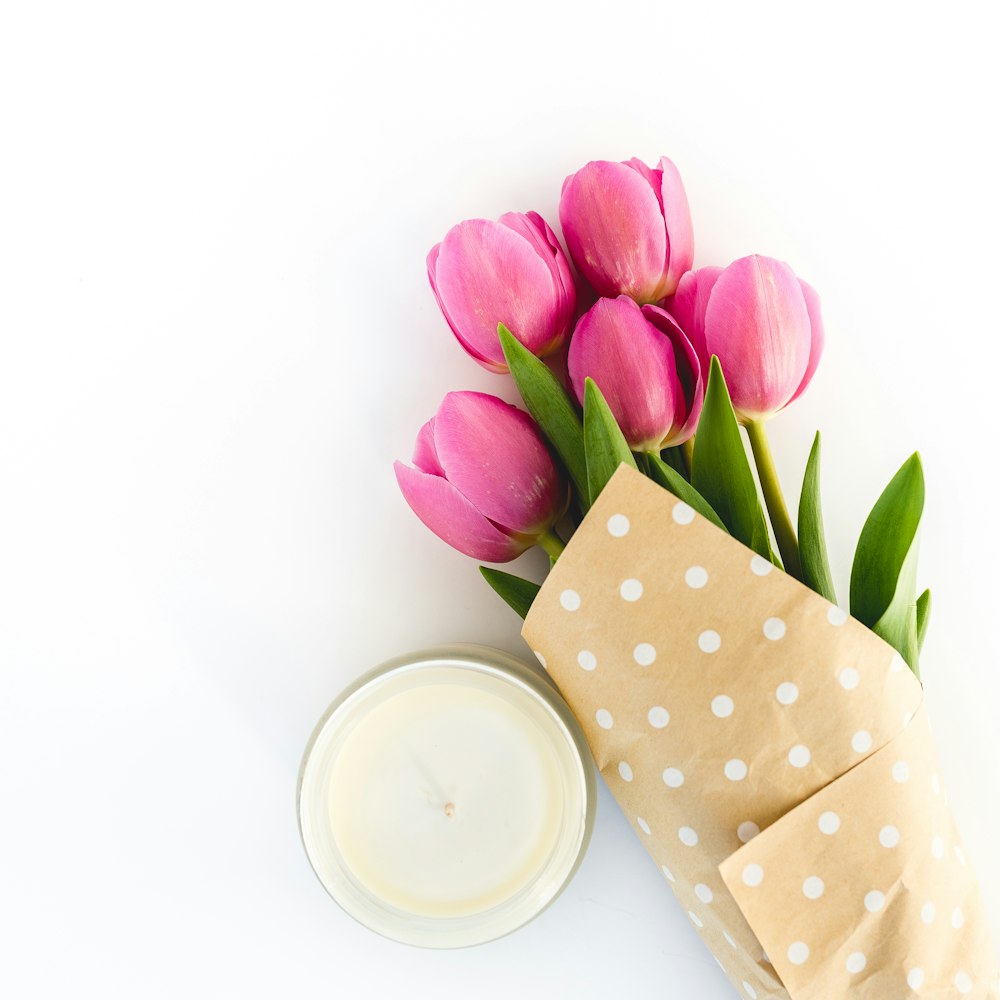Tulipanes rosas junto a cuenco de cerámica blanca con leche