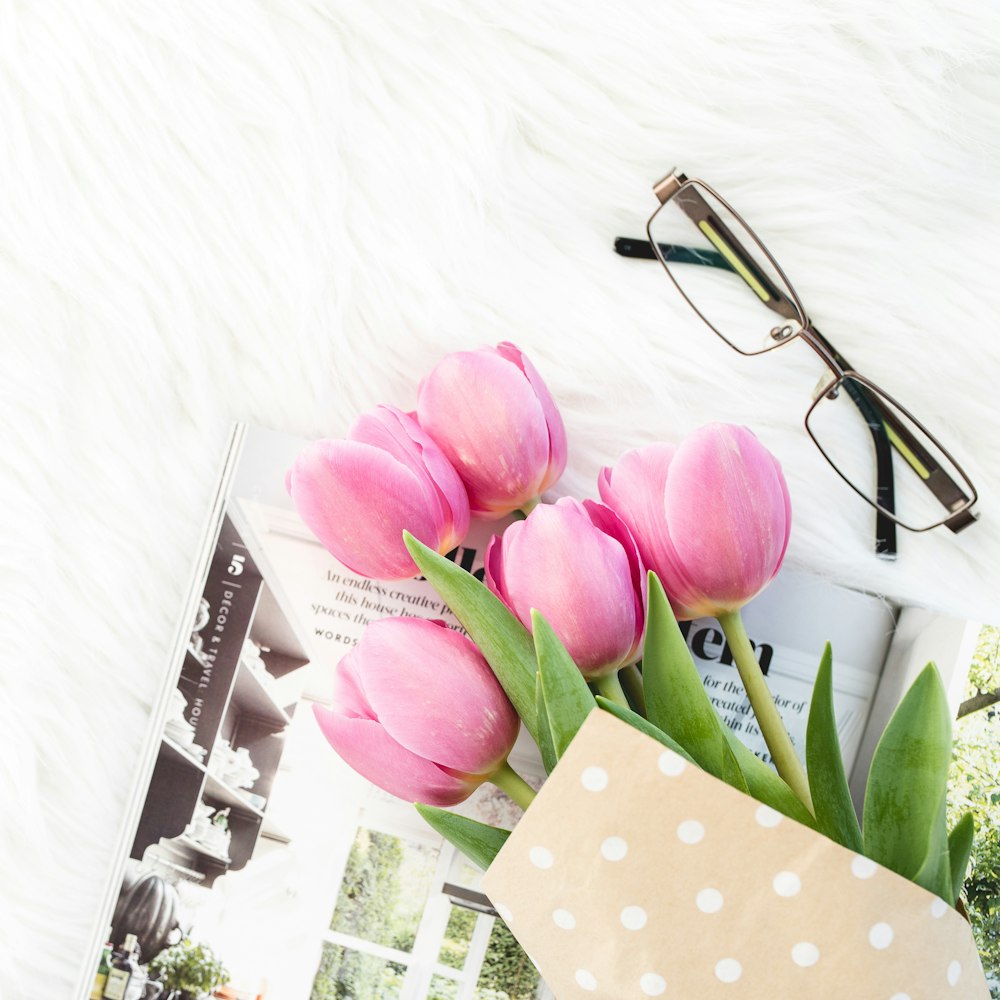 pink roses beside silver framed eyeglasses