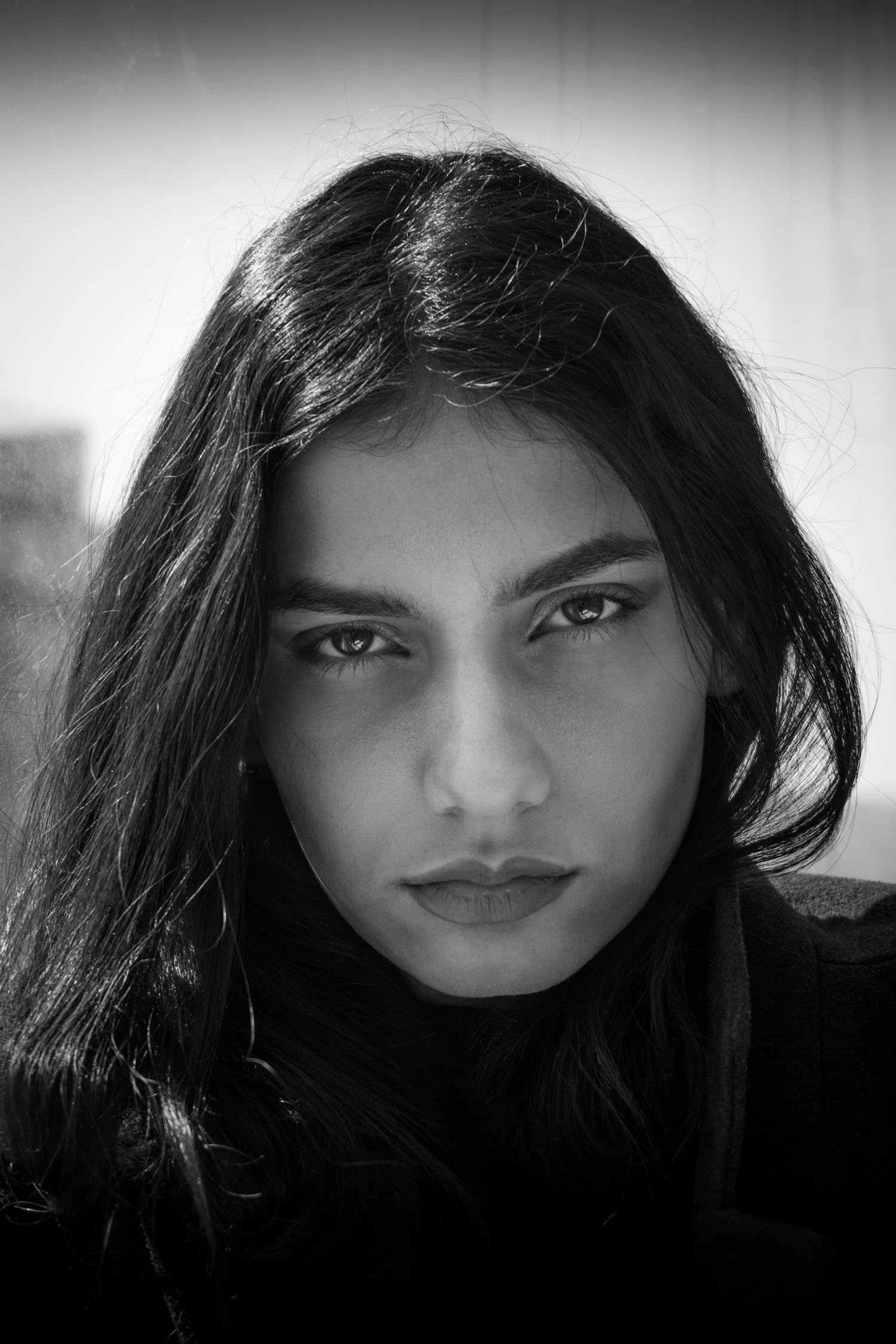 A woman's face half in shadow, lit by a single window on the left