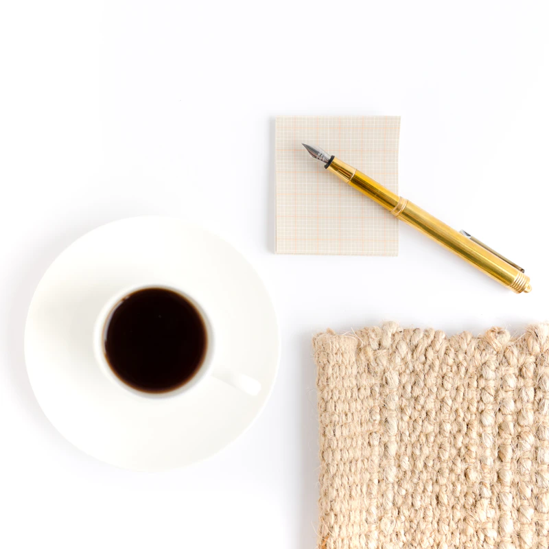 A white mug beside a brown pencil on a plate