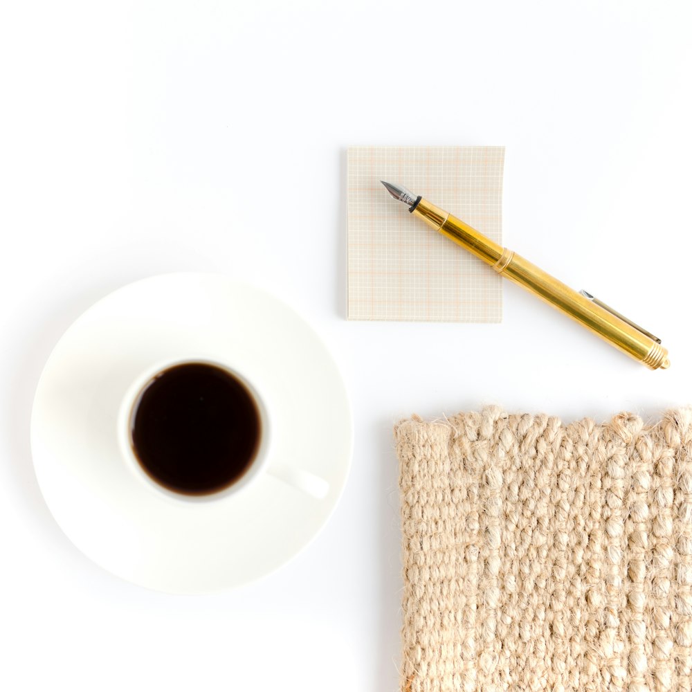 white ceramic mug beside brown pencil on white round plate