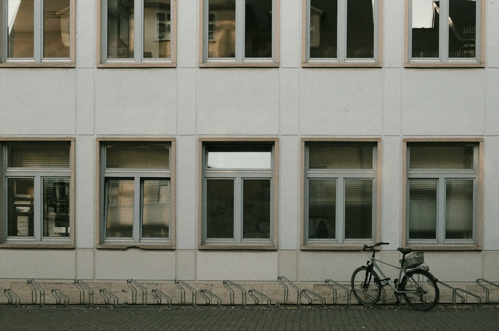 black bicycle parked beside white concrete building
