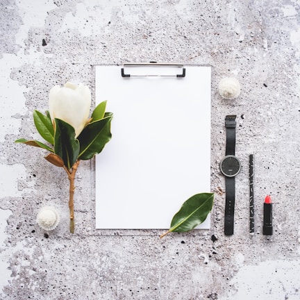 Minimalist composition of a vintage diary and a red lipstick on a cream background.