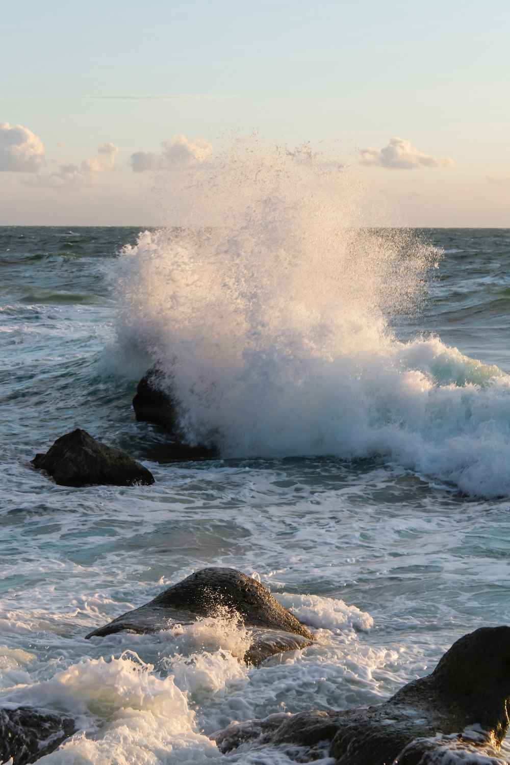 ocean waves crashing on black rock formation during daytime