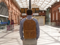 man in brown and black backpack standing on sidewalk during daytime