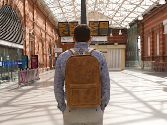 man in brown and black backpack standing on sidewalk during daytime
