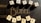 Wooden Scrabble tiles spell out 'Happy Easter' arranged over a dark surface with the word 'BIBLE' visible in gold lettering underneath. The tiles cast soft shadows, creating a warm and inviting atmosphere.
