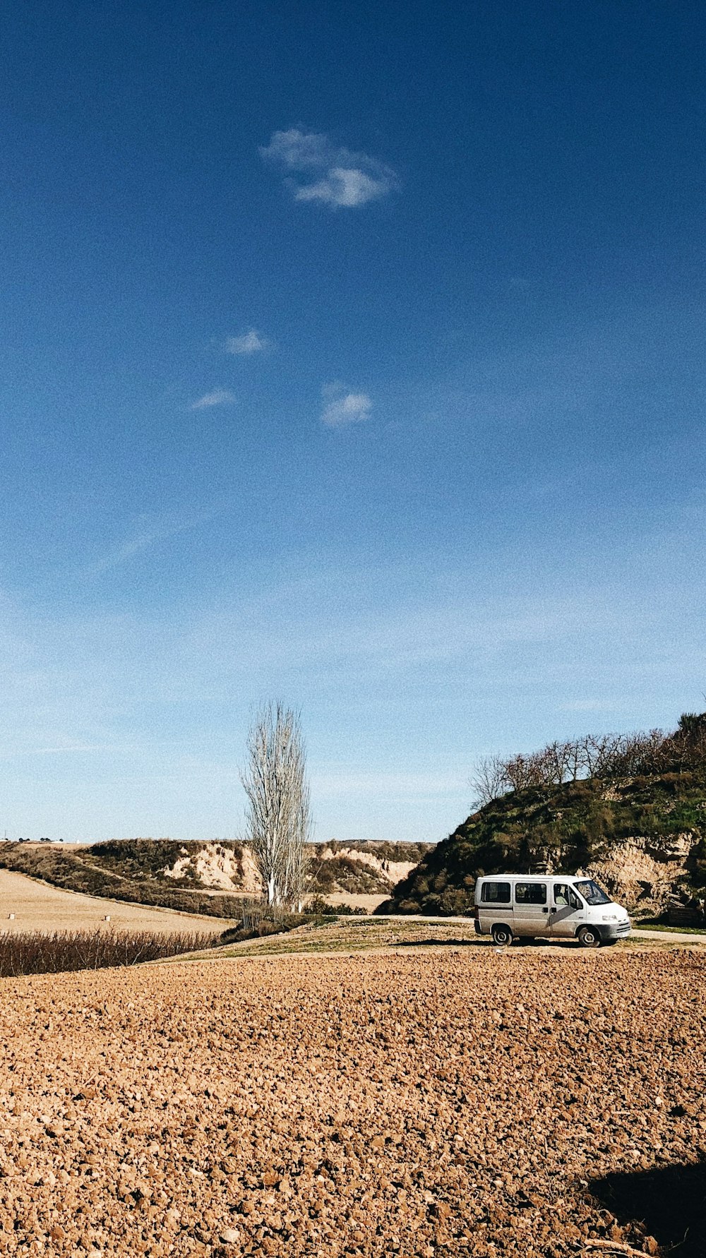 white van on brown field under blue sky during daytime