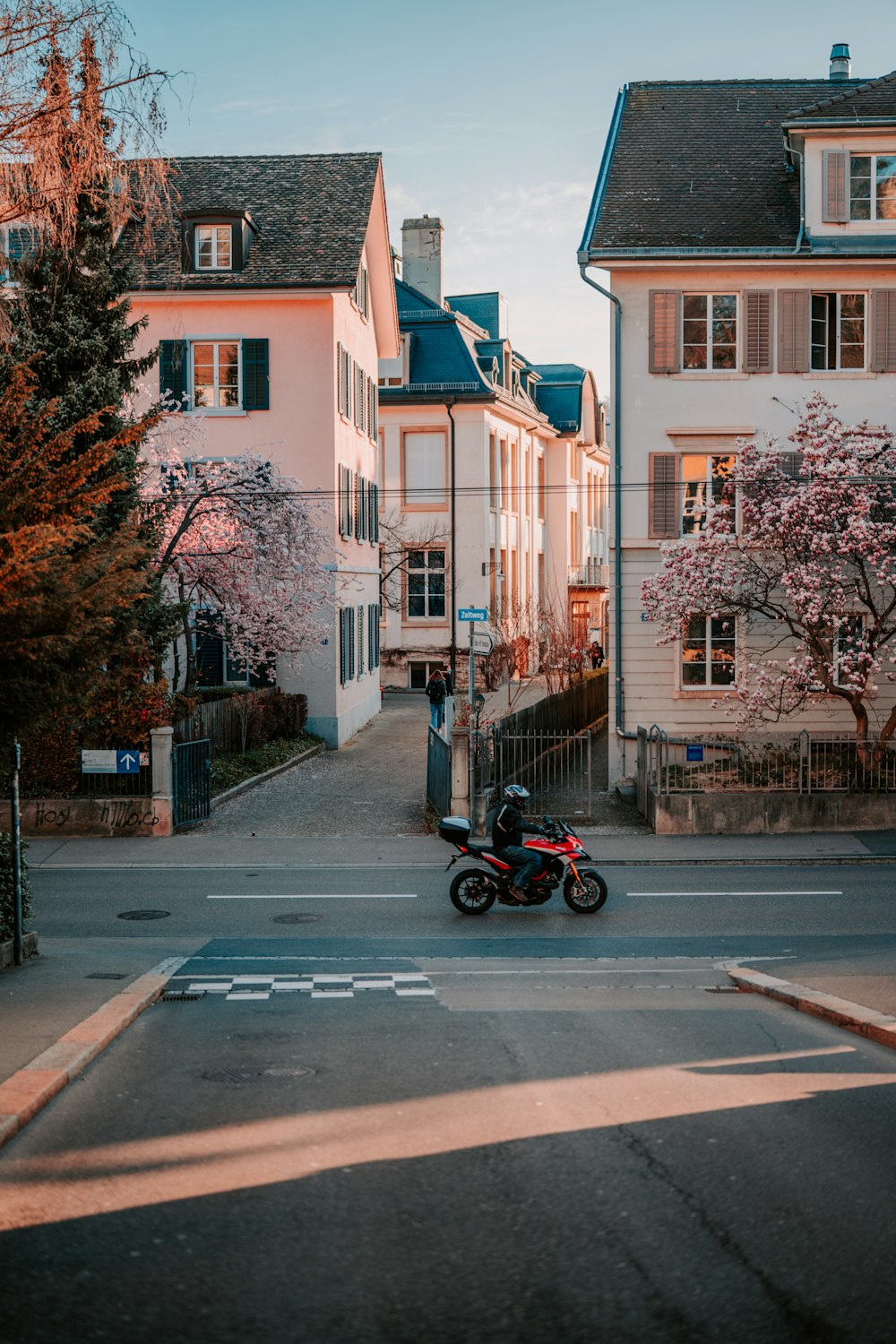 Rotes und schwarzes Motorrad tagsüber auf dem Bürgersteig in der Nähe des braunen Betongebäudes geparkt