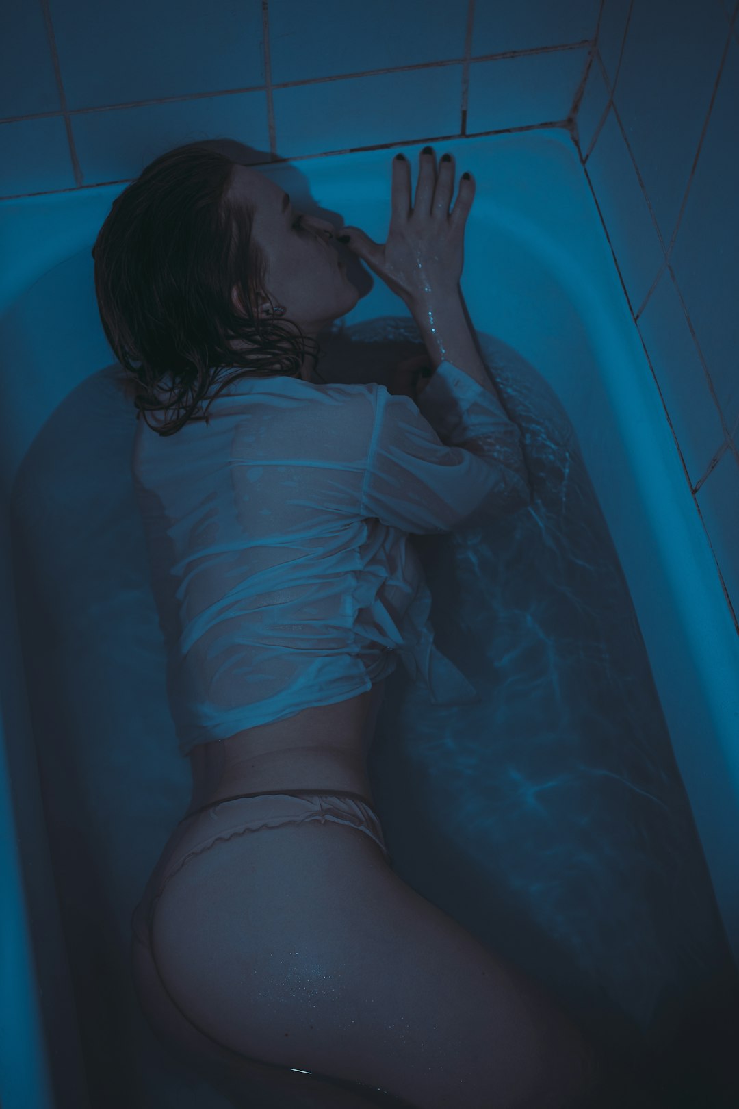 woman in blue shirt lying on bathtub