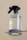 A clear spray bottle with a black trigger nozzle is placed on a glass surface. The bottle is transparent, partially filled with liquid, and has the word 'kinfill' printed on it.