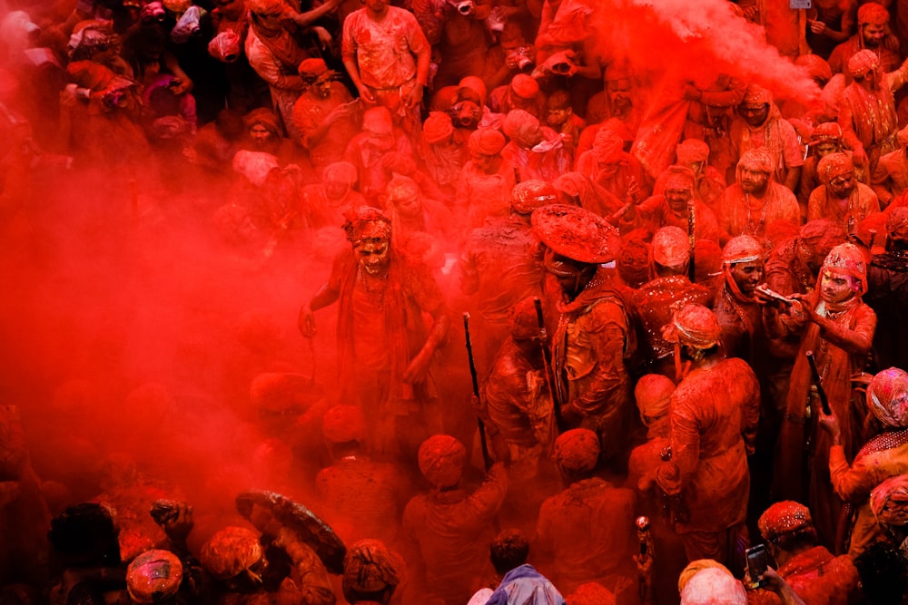 people in blue shirts with red powder on their hands