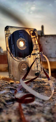 A vintage cassette tape glowing under neon lights with a backdrop of an 80's style cityscape at night.