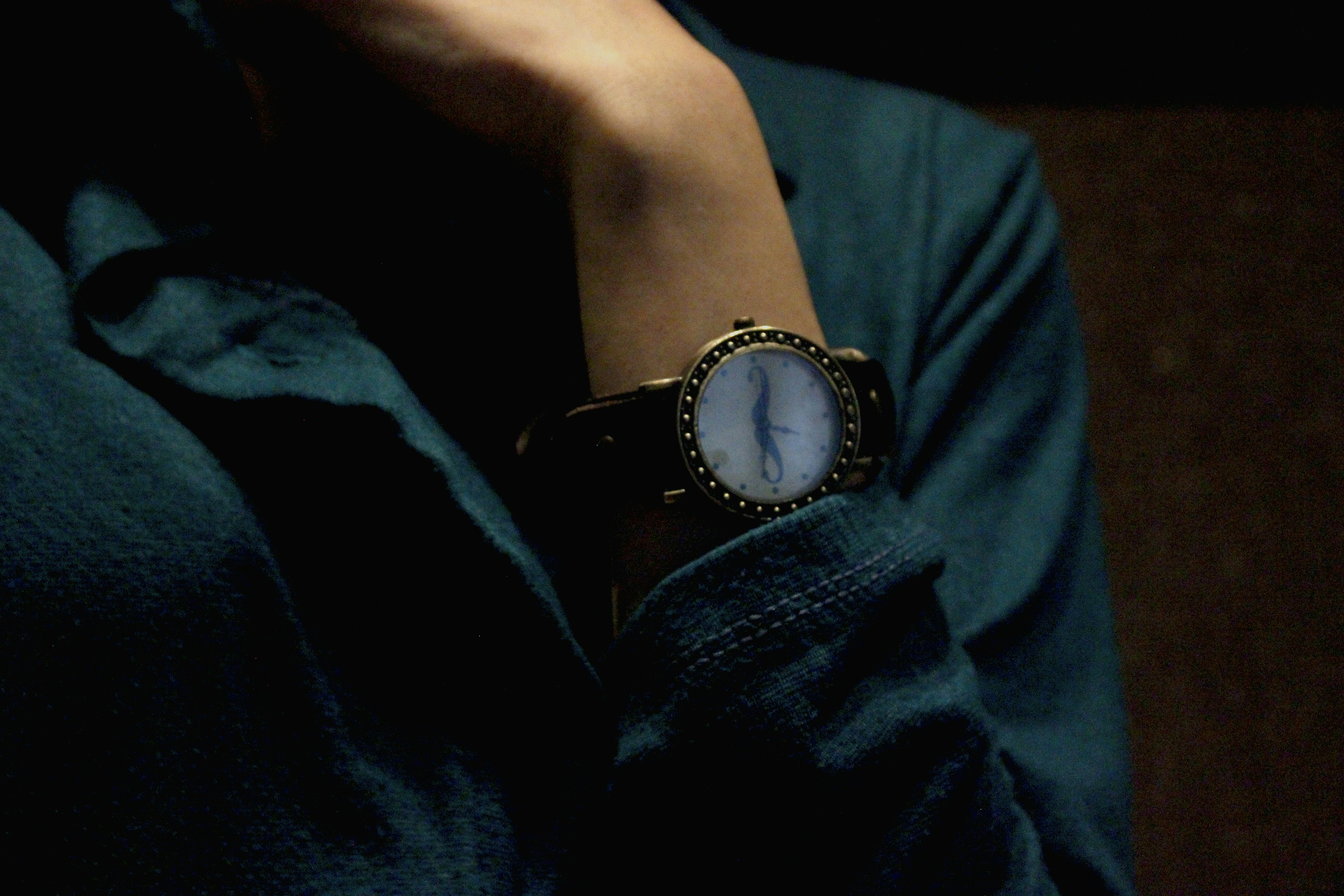 Person mit schwarzem Lederarmband silberne runde analoge Uhr