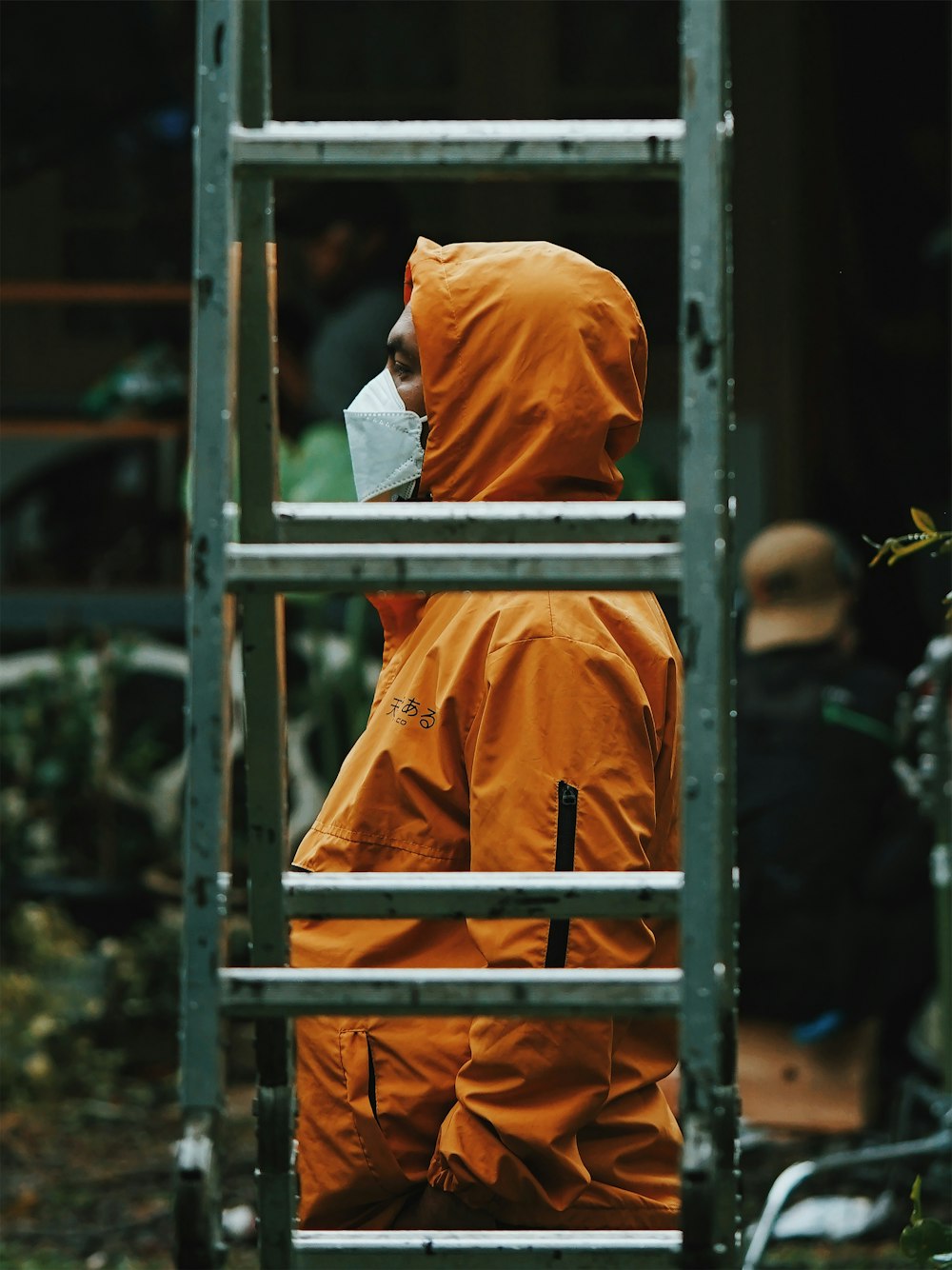 man in orange hoodie standing near brown wooden fence