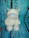 A plush toy of a dog with a white body, gray snout, and blue nose is placed against a backdrop resembling cracked, painted blue and brown wood.