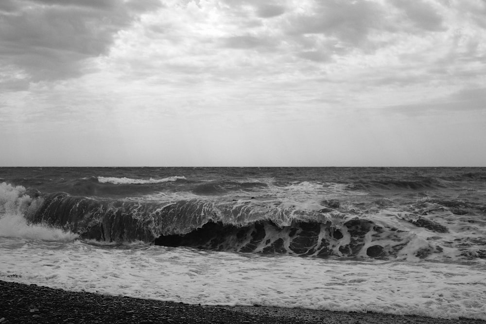 grayscale photo of ocean waves crashing on rocks